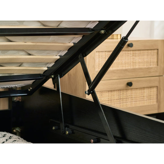 Black metal bed frame with wooden drawers in the background
