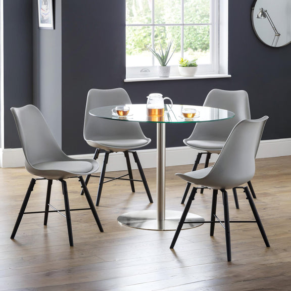 Dining room with a round glass table and four gray chairs on a wooden floor.