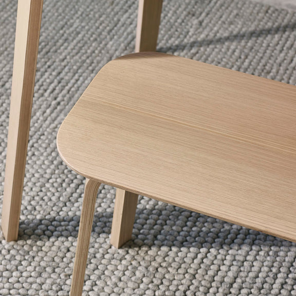 Close-up of a wooden chair on a textured gray carpet