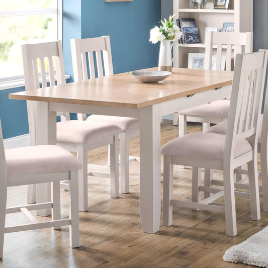 Dining room with a wooden table and white chairs against a blue wall.