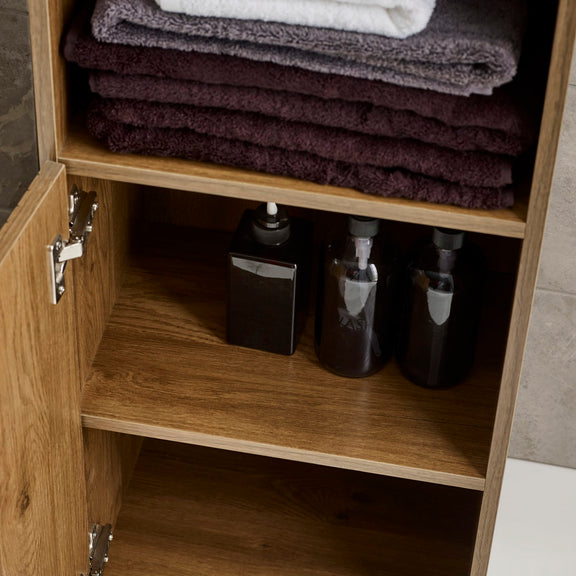 Wooden cabinet with folded towels on top and bottles inside