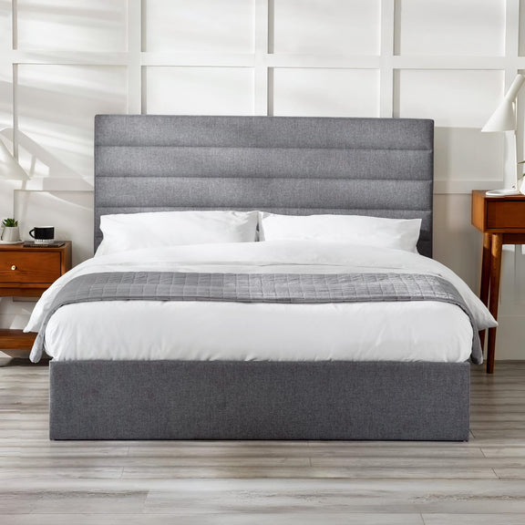 Gray upholstered bed with white bedding in a modern bedroom setting.