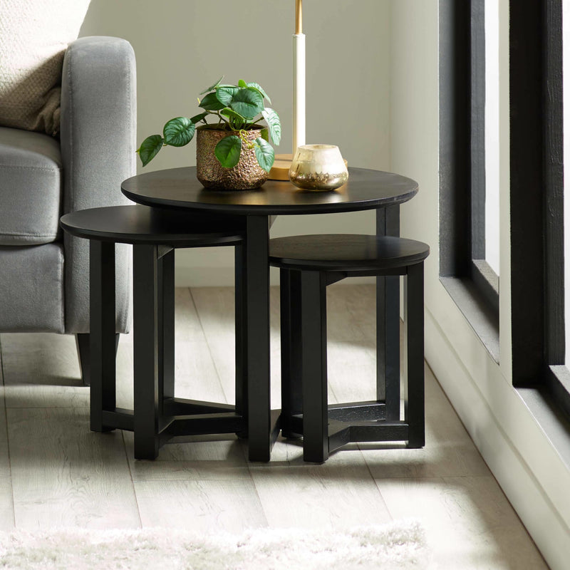 Black round table with a plant and candles in a living room setting