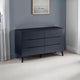 Dark blue dresser against a gray wall with a framed picture.