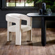 Beige chair next to a black dining table with decorative items on a wooden floor.