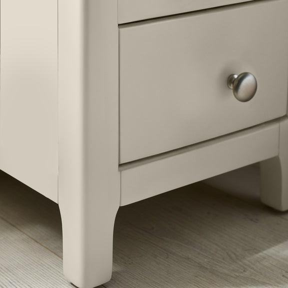 Close-up of round metal drawer knob on white bedside table
