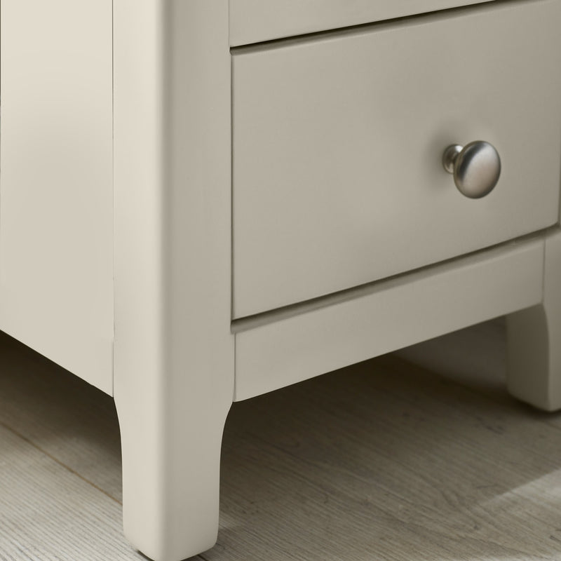 Close-up of round metal drawer knob on white bedside table