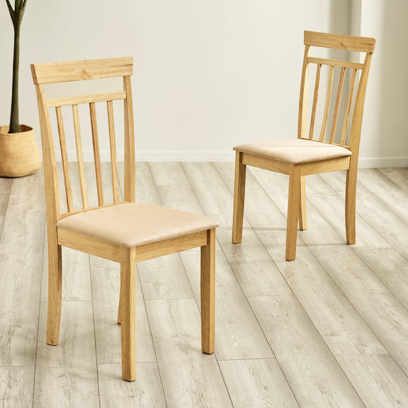 Two wooden chairs with beige cushions on a light wooden floor.