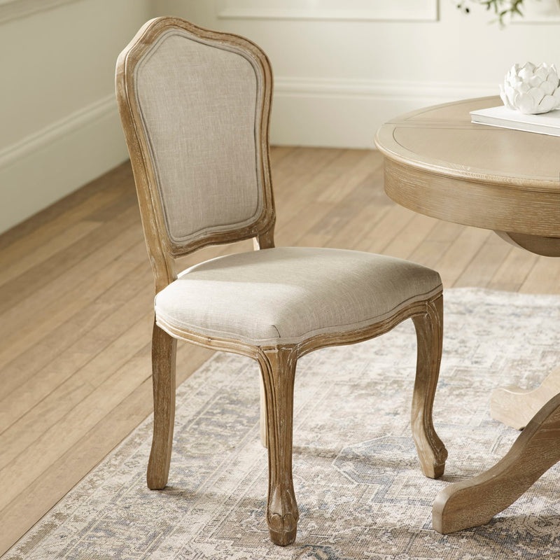 Wooden chair with beige cushioned seat and backrest in a room with wooden floor and table.
