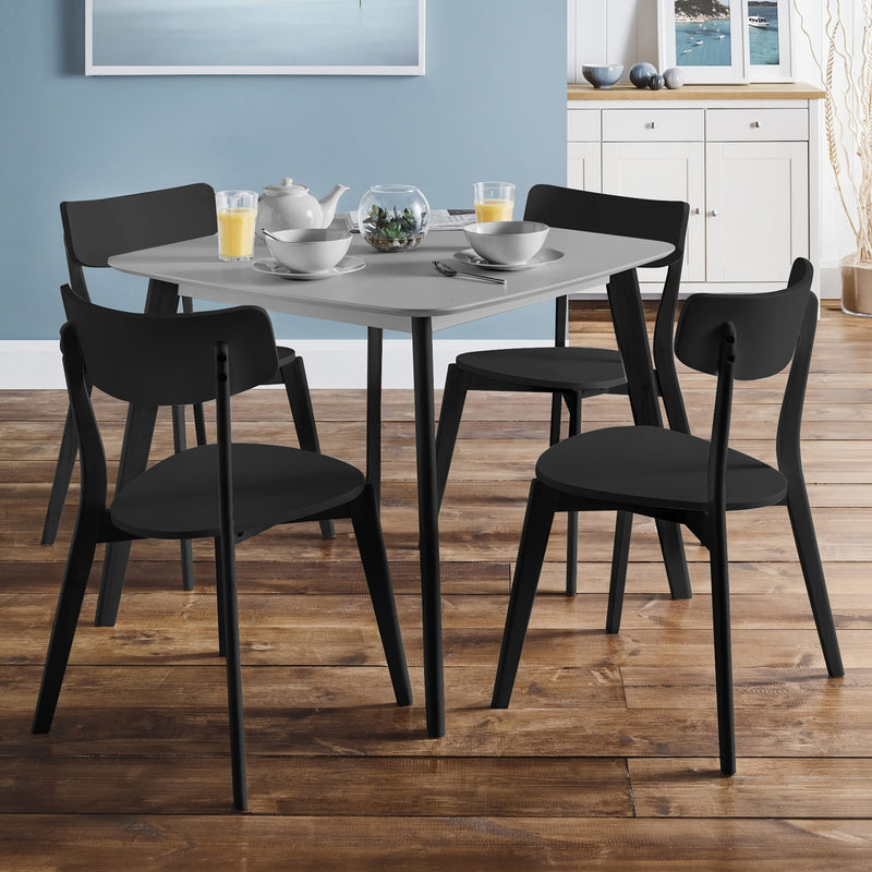 Dining table set with black chairs in a room with wooden flooring and a blue wall.