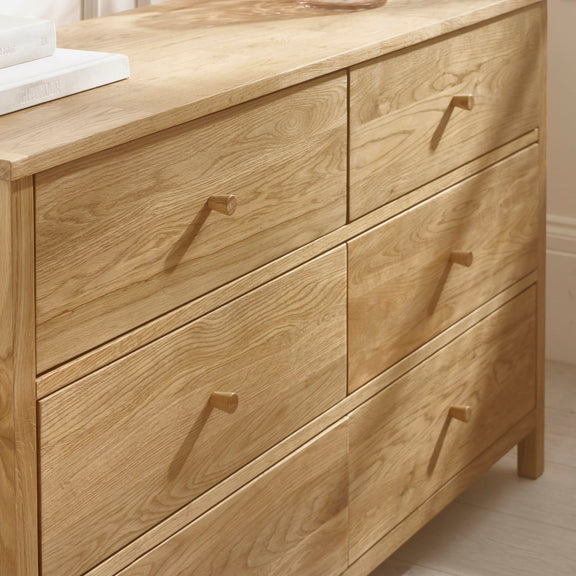 Wooden dresser with four drawers in a neutral setting