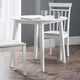 White dining table with two chairs in a room with gray walls and wooden flooring.