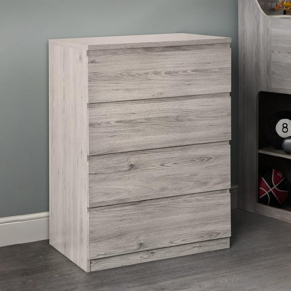 Wooden dresser with four drawers against a gray wall.