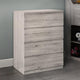 Wooden dresser with four drawers against a gray wall.