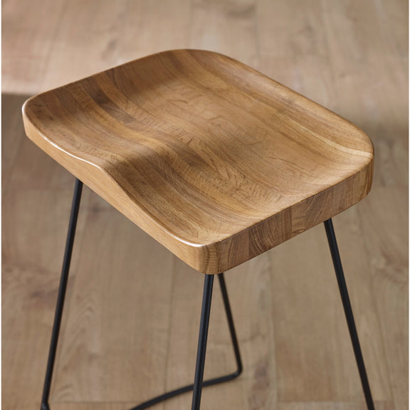 Wooden stool with black metal legs on a wooden floor.