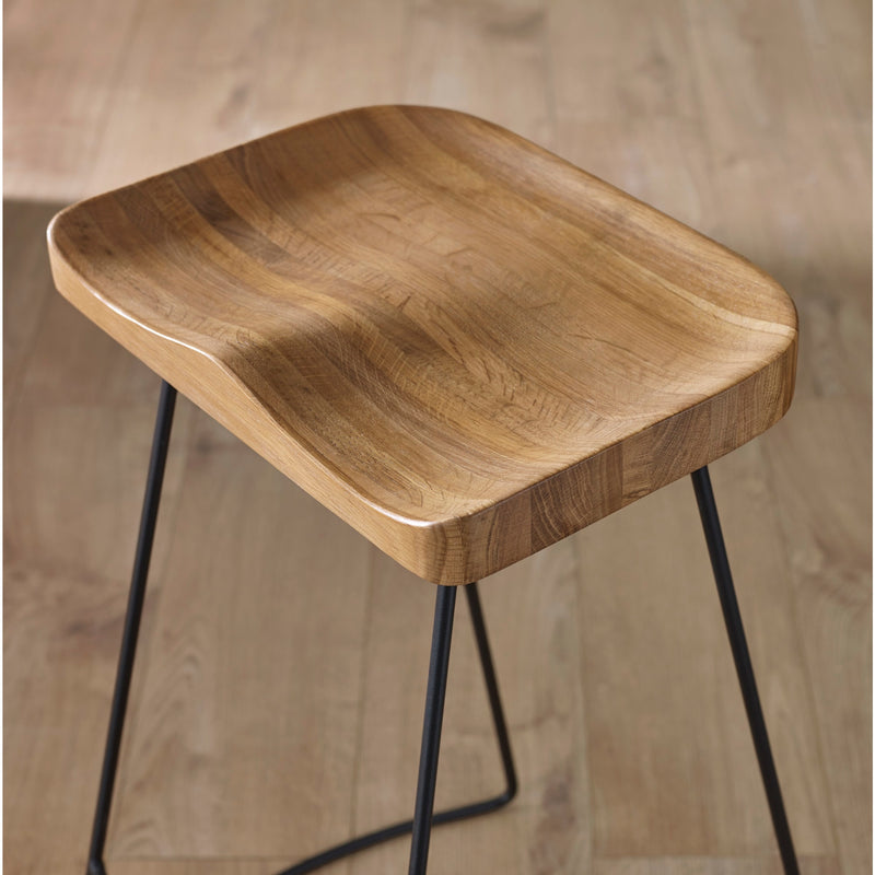 Wooden stool with black metal legs on a wooden floor.