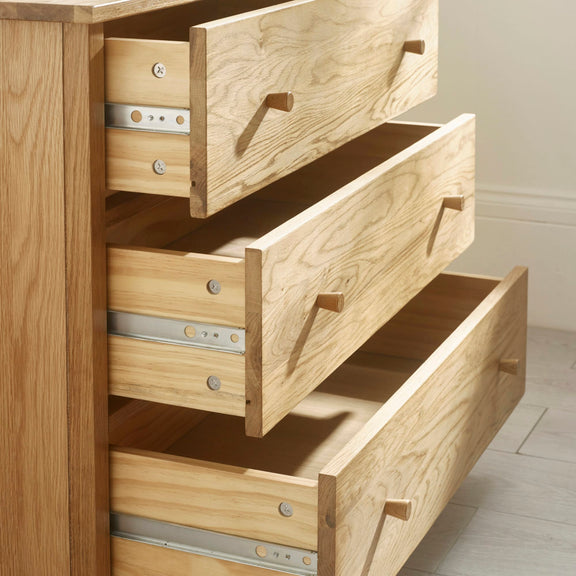 Wooden dresser with open drawers on a light wooden floor.