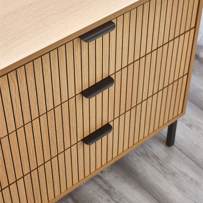 Wooden cabinet with slatted design and black handles on a light wooden floor.