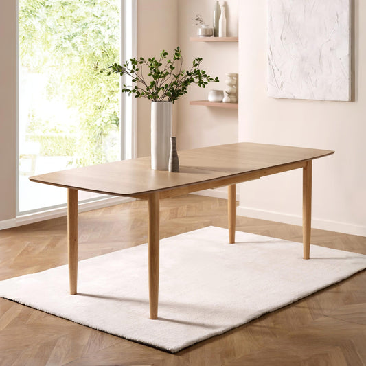Wooden dining table in a modern room with a large window and decorative elements.
