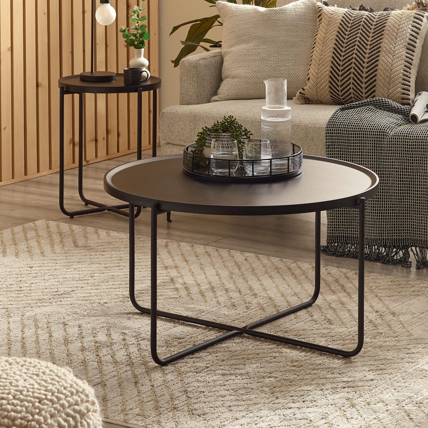 Round black coffee table in a living room setting with a couch and side table.