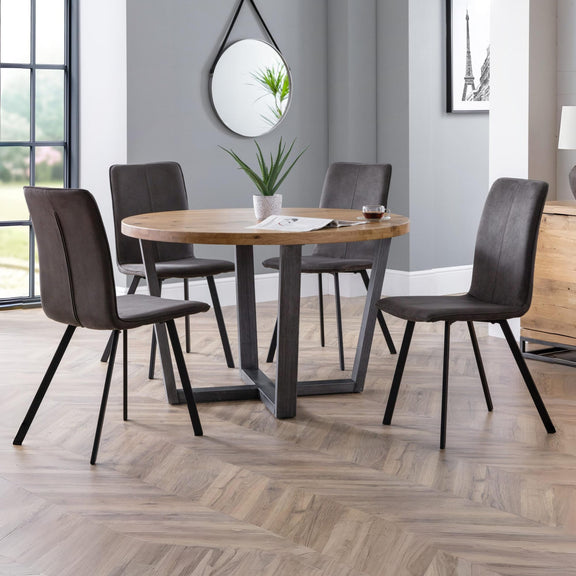 Dining room with a round wooden table and four brown chairs on a wooden floor.
