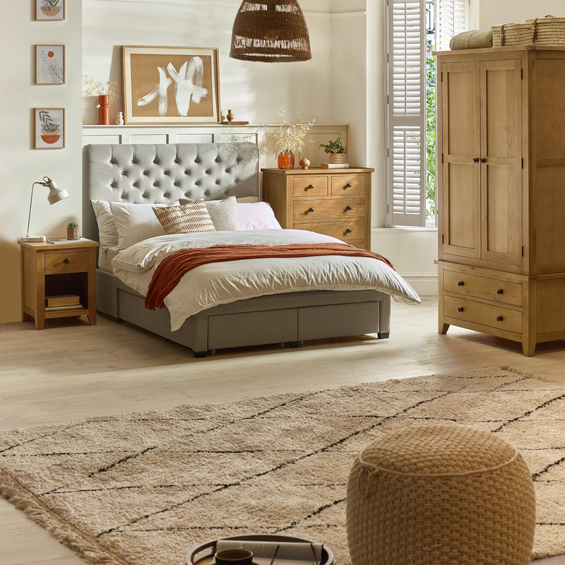 Bedroom with gray upholstered bed, wooden wardrobe, and decorative elements.