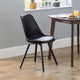 Black chair in a room with a wooden table and window sill with plants.