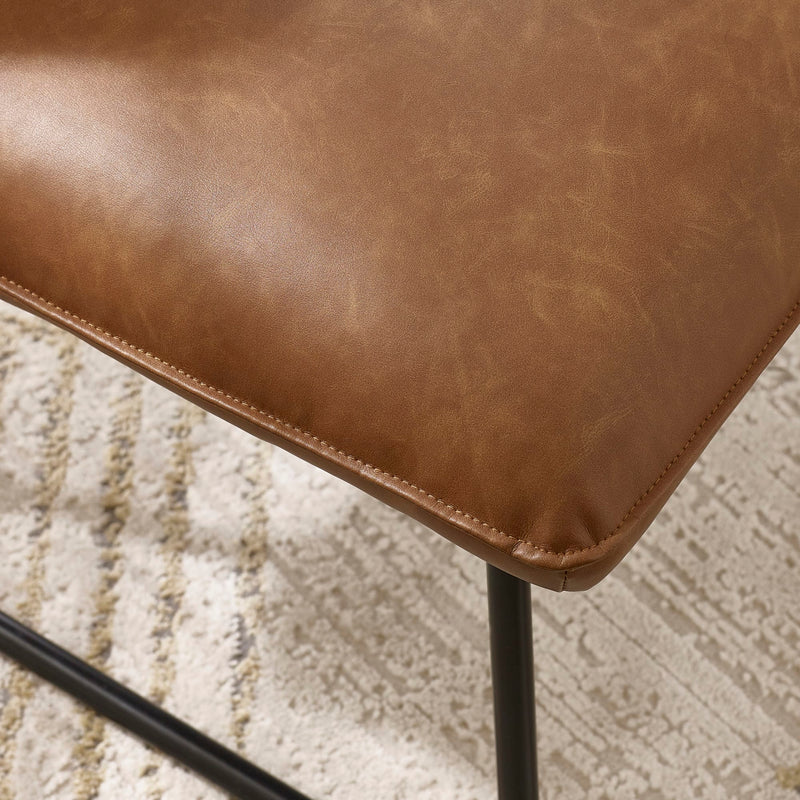 Close-up of a brown leather chair seat on a textured beige carpet