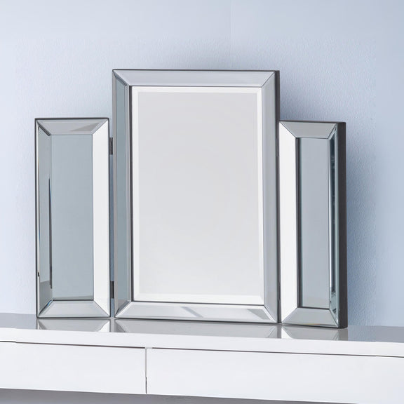 Three rectangular mirrors with silver frames on a white surface against a light blue wall.