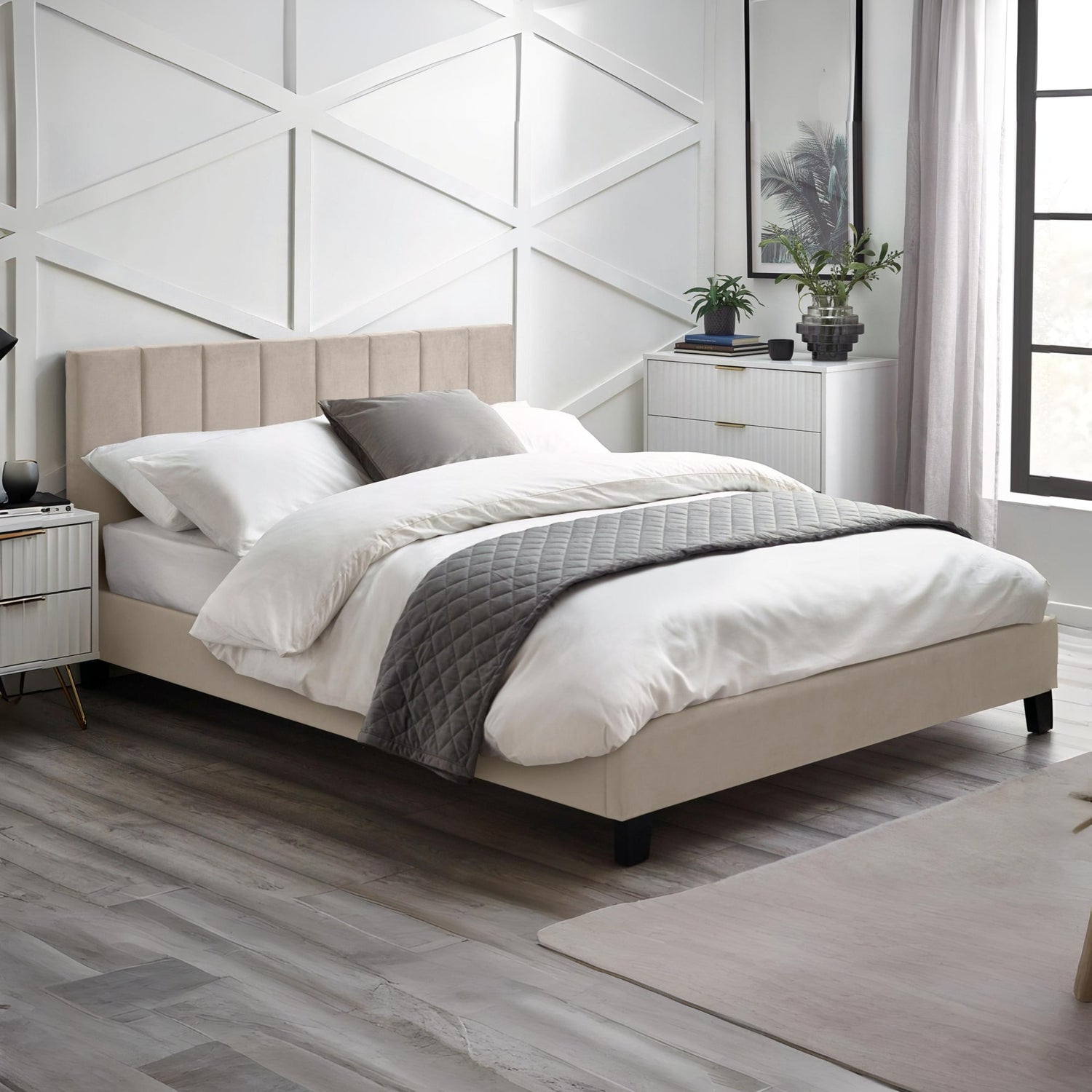 Neatly made bed in a modern bedroom with white walls and wooden flooring.