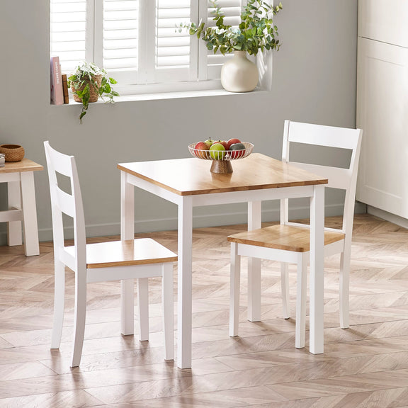 Dining area with a wooden table and white chairs in a room with a window and plants.