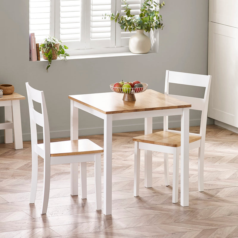 Dining area with a wooden table and white chairs in a room with a window and plants.