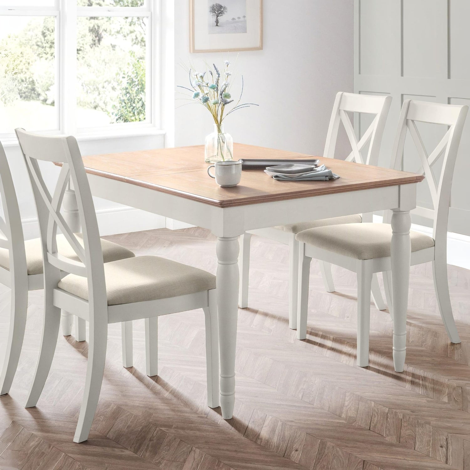 Dining room with a wooden table and white chairs on a wooden floor.