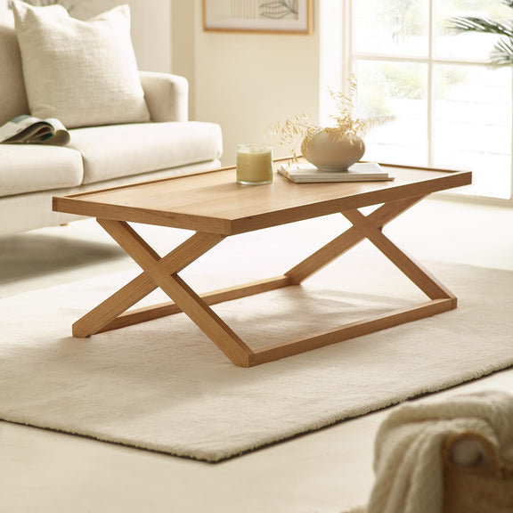 Wooden coffee table in a living room setting with a couch and decor items.