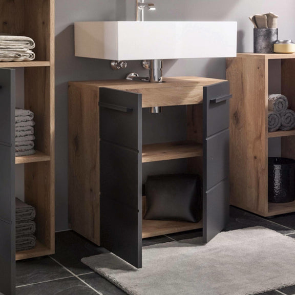 Bathroom vanity with wooden cabinets and a sink, surrounded by towels and decorative items.