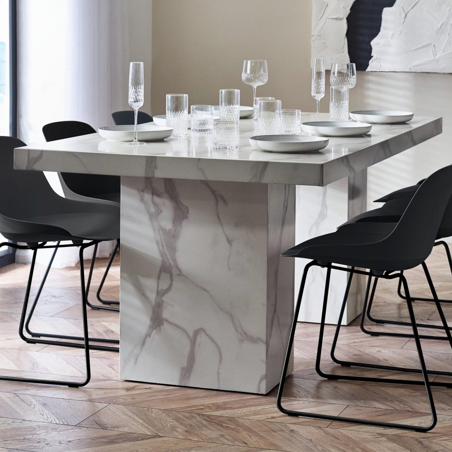 Dining table with marble finish and black chairs in a modern setting