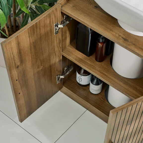 Wooden bathroom cabinet with open door revealing toiletries and a plant.