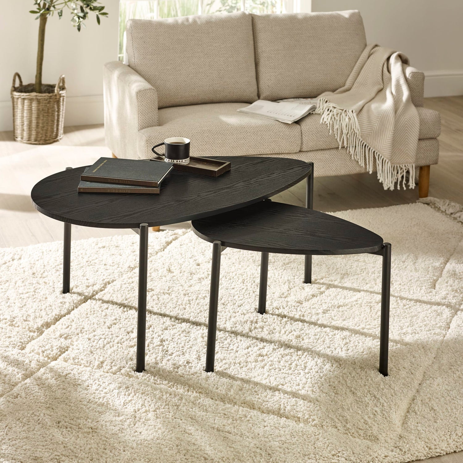Black nesting tables in a living room setting with a beige sofa and decor.