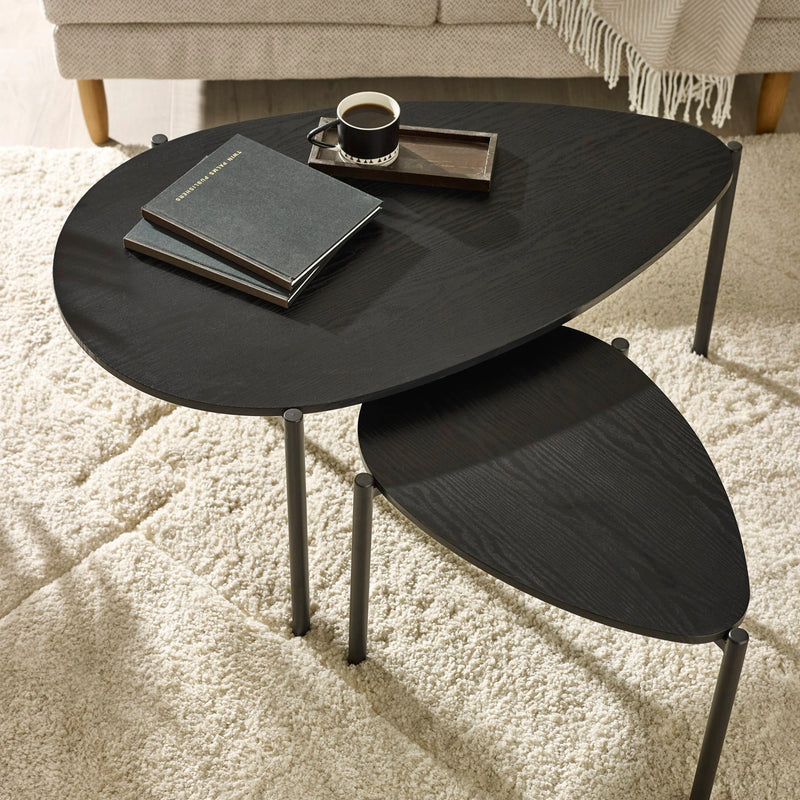 Black nesting tables with a cup and books on a light carpet