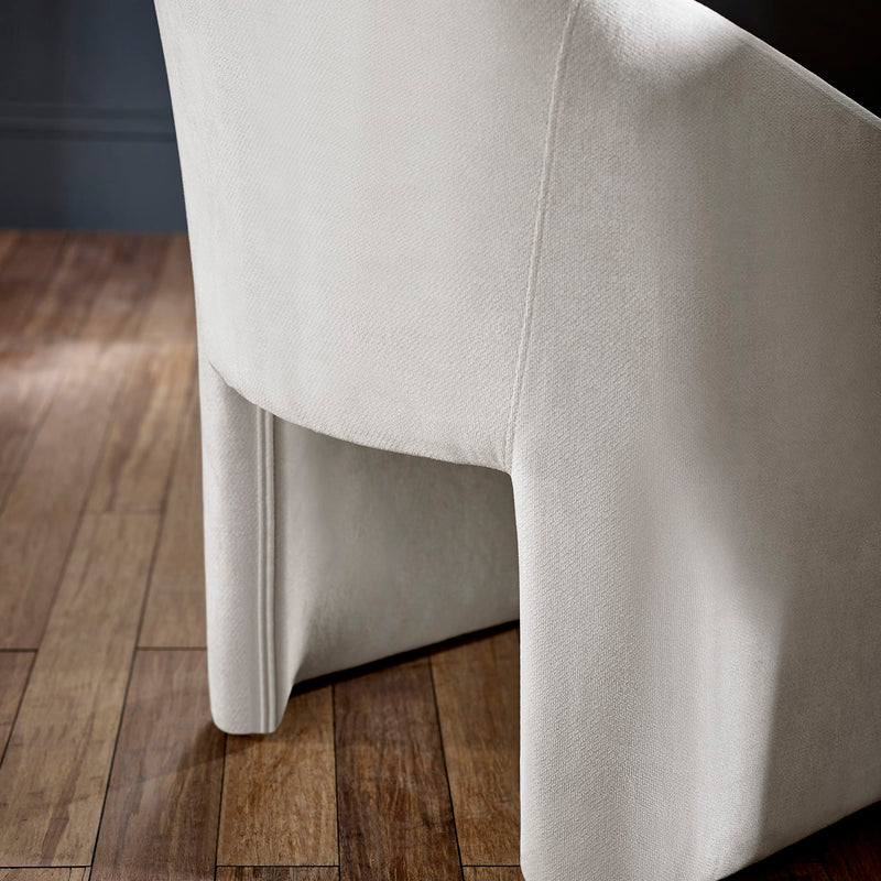 Close-up of a light gray upholstered chair on a wooden floor.