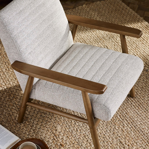 Gray upholstered chair with wooden arms on a textured beige carpet
