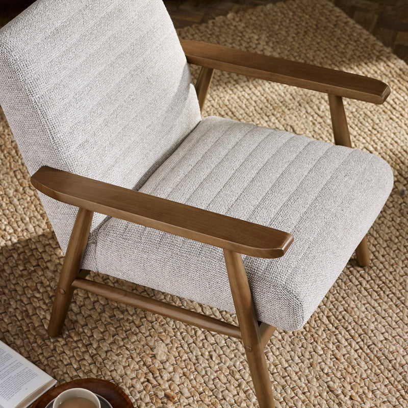 Gray upholstered chair with wooden arms on a textured beige carpet