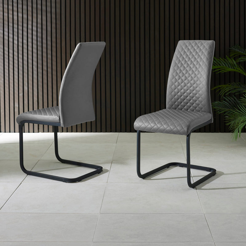 Two gray chairs with quilted design on a tiled floor.