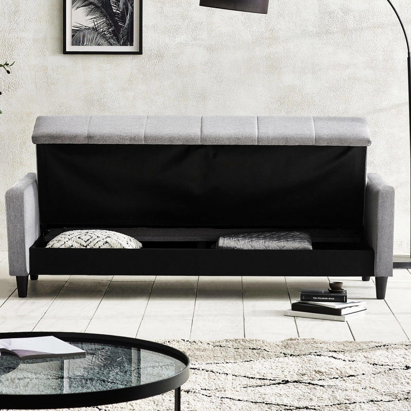 Gray upholstered bench with black cushioned storage space in a modern living room.