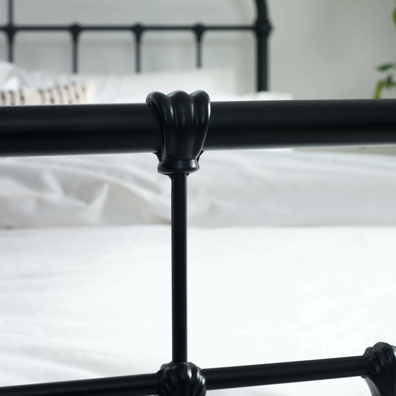 Black metal bed frame with decorative claw-hold feet against a white background