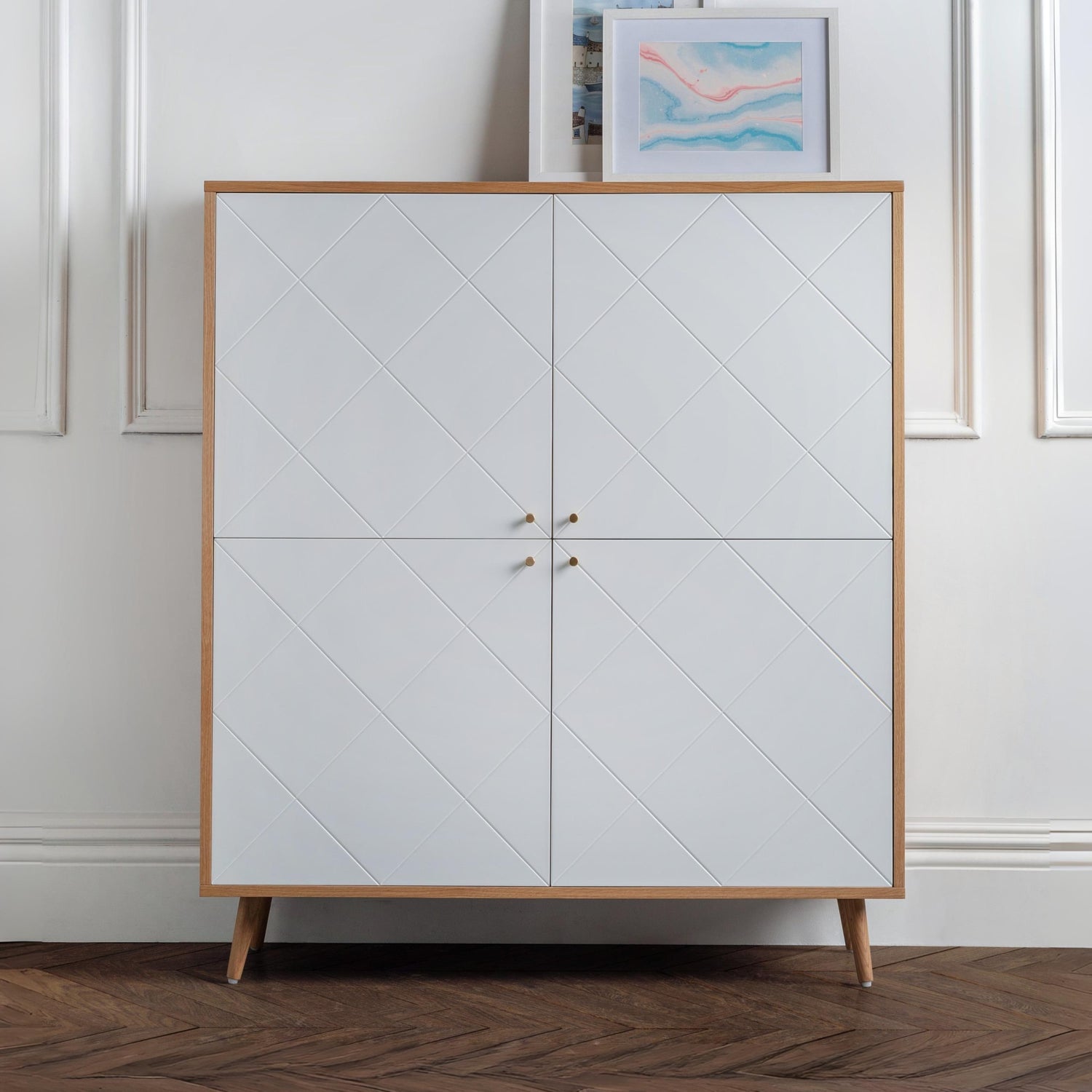 White cabinet with wooden frame and legs against a white wall