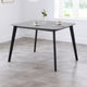 Dining table with a gray top and black legs in a room with a window.