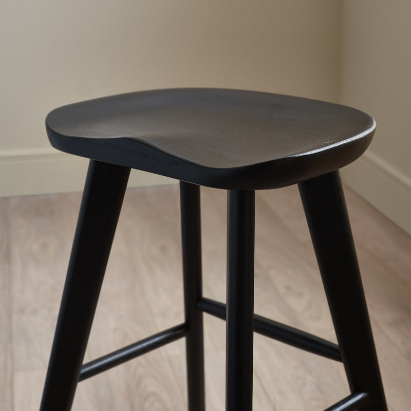 Black stool against a neutral wall