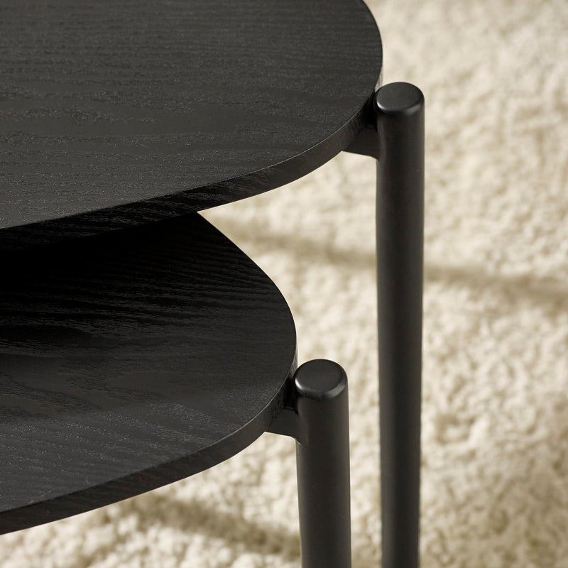 Close-up of a black metal side table with a textured white background
