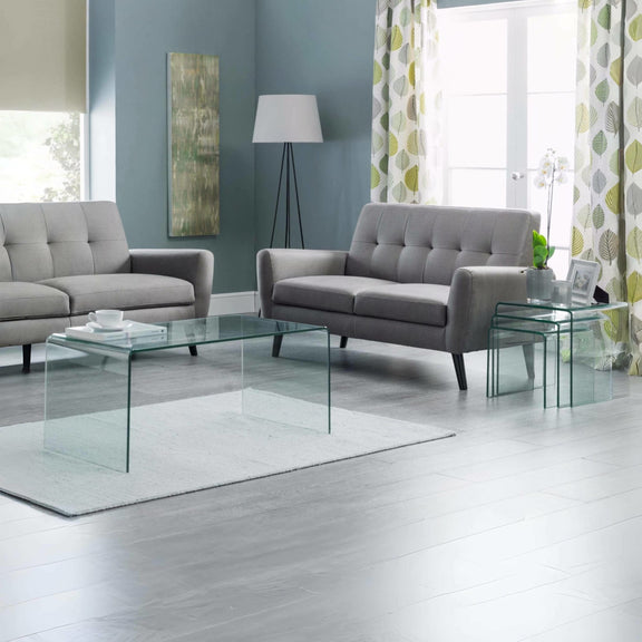 Modern living room with gray sofas, glass coffee table, and decorative elements.